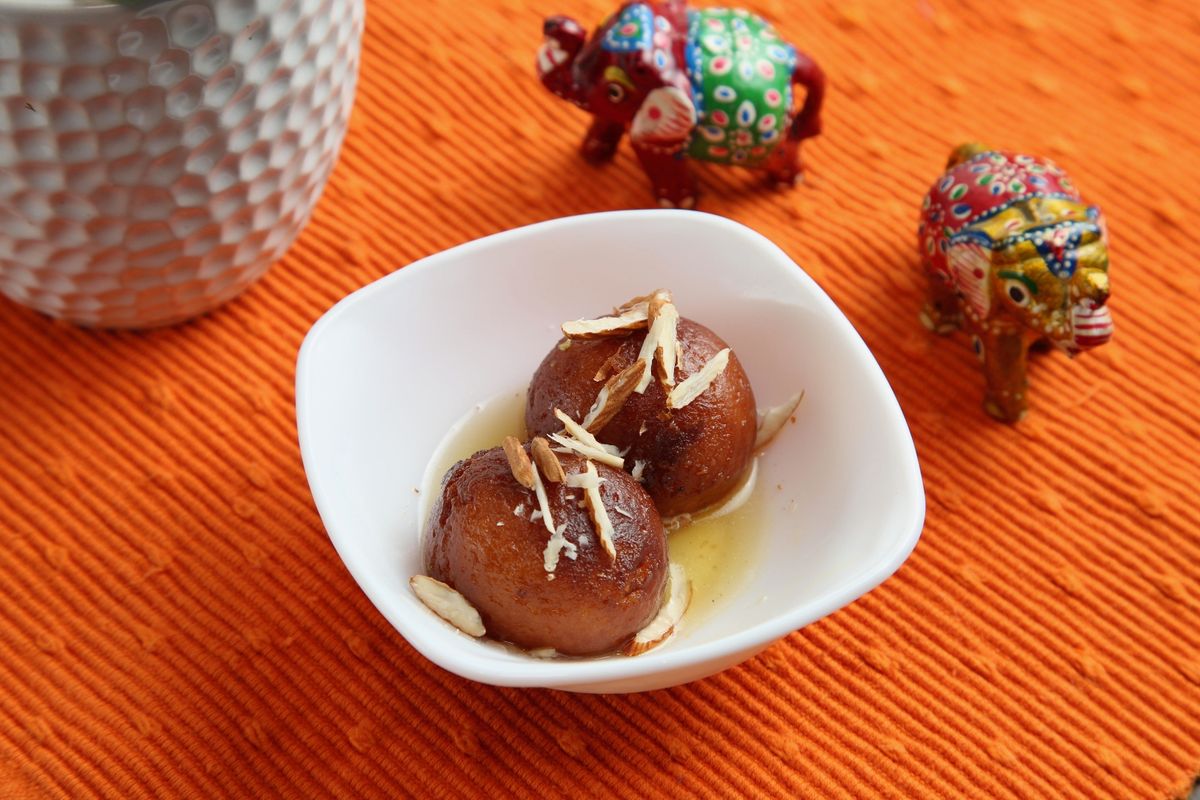 Warm gulab jamun soaked in syrup and topped with almonds
